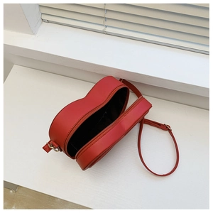 Dettaglio di una borsa a tracolla rossa a forma di cuore con cerniera dorata