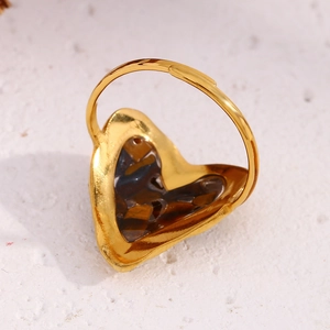 Macro detail of 18K gold-plated heart ring featuring a dark tiger eye stone inlay