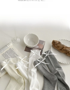 Detail of ribbed knit crew socks with white silk ribbons in neutral color tones