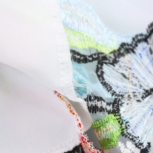Dettaglio ricamo floreale su abito lungo bianco a vita alta in tulle velato