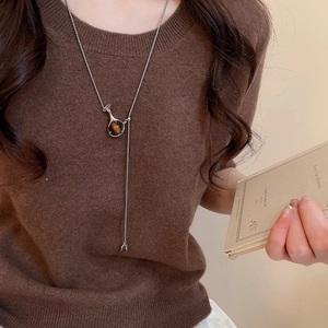 Silver Y-necklace with tiger eye pendant on brown knit sweater for a vintage look