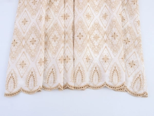 Detailed close-up of bohemian ivory dress hem featuring geometric diamond embroidery and lace