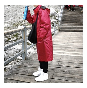 Outdoor view of a long hooded red raincoat with premium waterproof coating for hiking