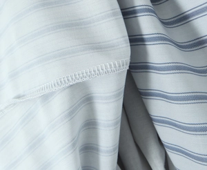 Close-up of the light blue striped fabric texture and neat stitching detail of the dress