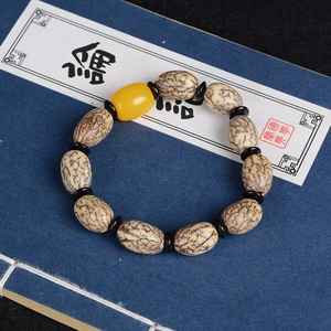 Bodhi-Samen Perlenarmband im Zen-Stil mit gelber Tonnenperle auf antikem Buch