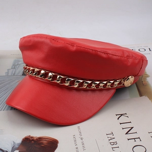 Detail of red PU leather baker boy hat with golden metal chain and side buttons