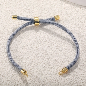 Close-up of grey Milan cord bracelet with adjustable gold-plated slider clasp and metal ends