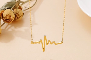 Macro view of a creative golden heartbeat pendant and elegant thin metallic link chain
