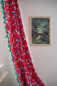 Close-up of Christmas cotton linen curtain with red floral print and green fringe trim