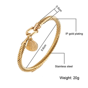 Macro view of gold stainless steel twisted bangle with San Benito coin charm details
