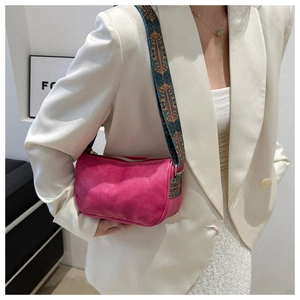 Close-up of pink crossbody bag with retro patterned strap and soft leather texture