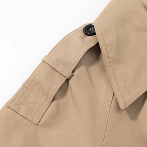 Detailed view of khaki trench coat shoulder with twill texture and black button