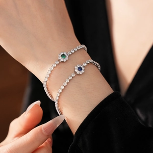 Detailed shot of flower bracelets with blue and green stones on a model wrist