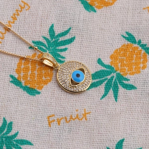 Close-up of gold-plated evil eye pendant necklace with blue stones and clear crystals