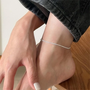 Detail view of a dainty S925 sterling silver anklet with sparkling zircon on a model ankle