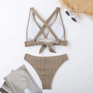 Flachbild eines khakifarbenen Ripp-Bikinis mit gekreuzten Trägern und Strandzubehör