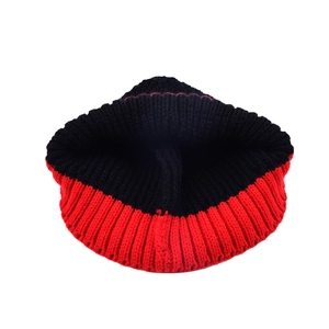 Détail du bonnet en maille bicolore rouge et noir montrant la texture côtelée épaisse