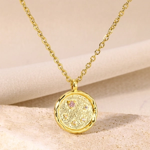 Macro view of 18K gold plated textured coin pendant with pink and white cubic zirconia