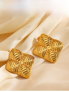 Macro shot of gold square stud earrings with radial texture on elegant silk fabric