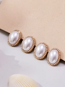 Close-up of vintage oval pearl earrings with sparkling rhinestones and gold metal base