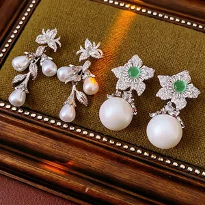 Vintage gold pearl drop earrings with zircon floral accents on green velvet tray