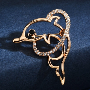 Macro detail of a gold dolphin brooch featuring sparkling rhinestones on blue surface