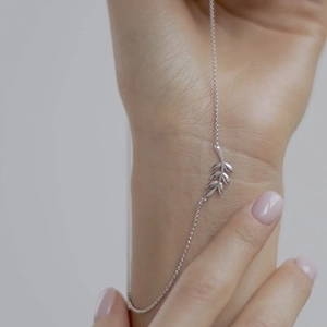 Close-up of a delicate 925 sterling silver bracelet featuring an olive leaf charm on wrist