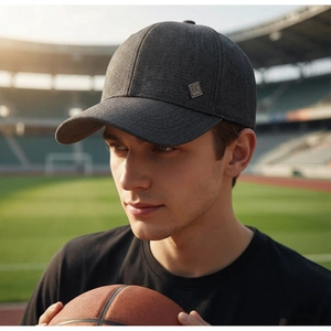 Detail of dark grey textured baseball cap featuring a square metal logo on the side
