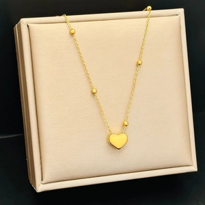 Minimalist 18K gold heart pendant necklace with beaded chain on jewelry display stand