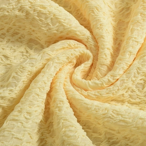 Détail macro du tissu seersucker jaune crème avec des motifs ondulés en relief 3D