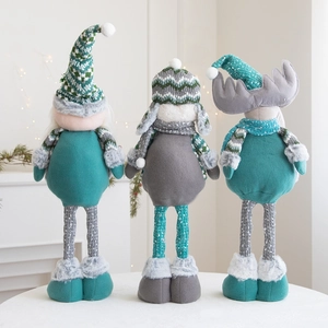 Close-up of plush Christmas dolls featuring knitted hats and scarfs on a cozy mantelpiece