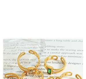 Detail of vintage gold-finished open rings featuring emerald green gemstones and twisted bands