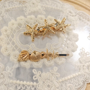 Golden starfish and seashell hair clips with pearls and rhinestones on lace background