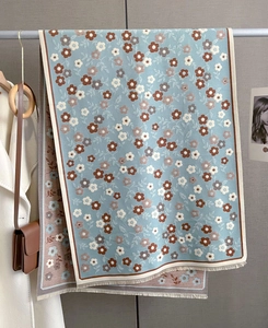 Detail of blue winter scarf with floral pattern and tassels on minimalist background