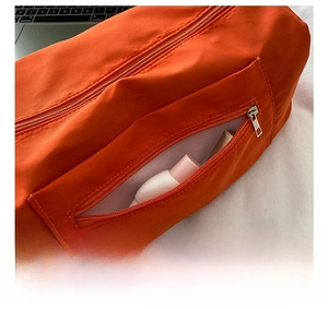 Detail view of the orange oxford crossbody bag showing the side zipper pocket and storage