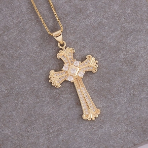 Dettaglio del ciondolo a croce placcato oro 18K con zirconi micro-pave su sfondo grigio