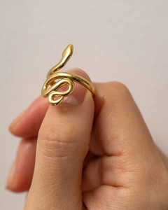 Detail of a minimalist gold snake-shaped wrap ring worn on a finger with a polished finish