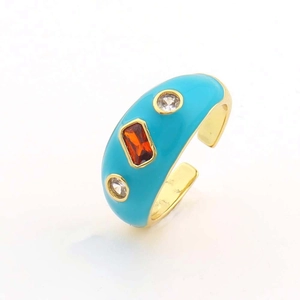 Dettaglio anello regolabile dorato con smalto blu e pietre di zircone rosso
