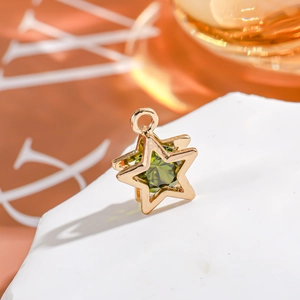 Macro view of a 14K gold-filled star pendant with a green zircon gem on a white stone