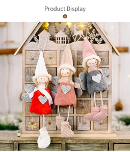 Close-up of three plush Christmas angel ornaments in red, pink, and grey with glitter wings