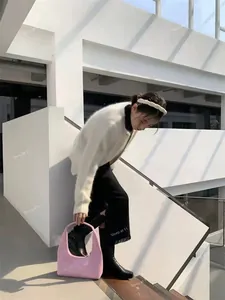 Pink patent leather crescent handbag styled with a white fuzzy cardigan and black skirt