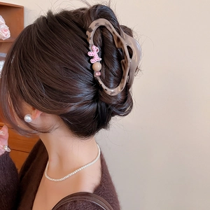 Detail view of leopard print hair claw with a pink cartoon puppy decor on hair bun