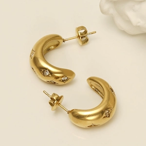 Détail de boucles d'oreilles dorées en forme de C avec zircons blancs et fini satiné