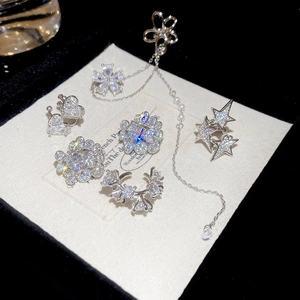 Détail de clips d'oreilles argentés avec cœurs, étoiles, zircon et franges chic