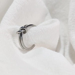 Macro view of minimalist silver knot ring with polished stainless steel texture