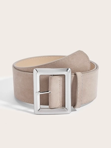 Détail d'une large ceinture en daim beige avec une boucle carrée en métal argenté poli