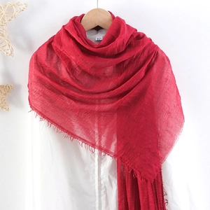 Detail of red crinkle cotton linen scarf with frayed edges hanging on wooden hanger