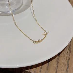 Elegant gold necklace with white enamel fish tail pendant and sparkling crystal details