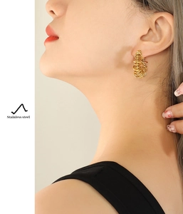 Close-up of a model wearing textured golden U-shaped stainless steel earrings