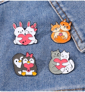 Close-up of four cute animal enamel pins including cats and bunnies on denim fabric